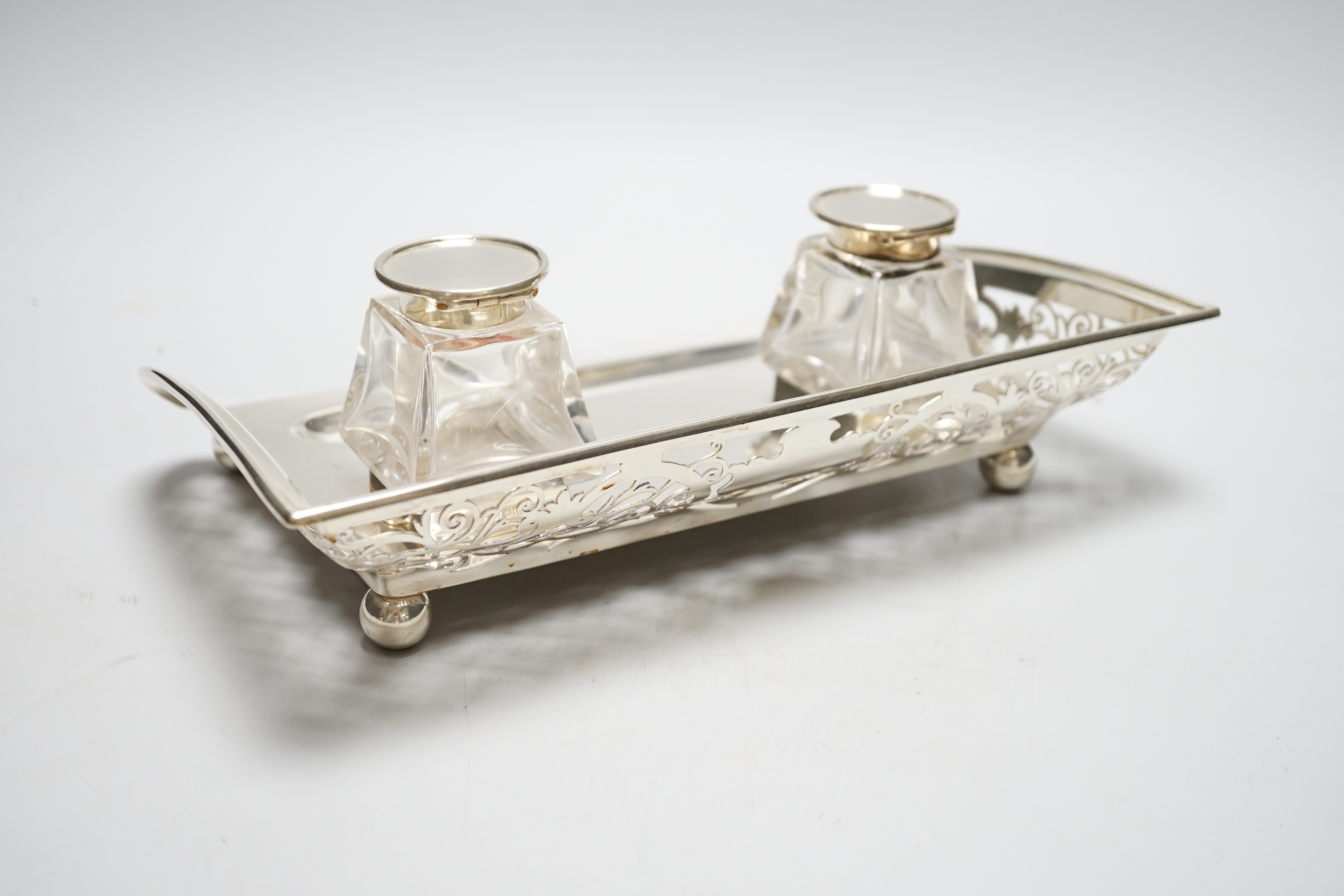 A George V pierced silver inkstand, with two mounted glass wells, Mark Willis & Son, Sheffield, 1912, length 29cm, base 21.7oz.